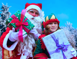 Weihnachtsmann und Weihnachtself Zimtstern präsentieren die Geschenke