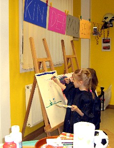 zwei Mädchen beim Malen auf Leinwand in einem als Kindermuseum dekorierten Innenraum