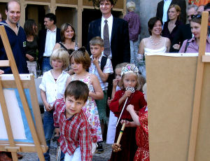 Vernissage: Kinder mit Spielleiter Robert Mingau und Hochzeitsgäste, die auf Staffeleien aufgestellte Bilder betrachten