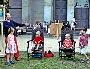 4 Kinder mit Spielleiter Robert Mingau bei einer Theaterprobe auf grüner Wiese