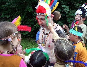 Spielleiter Robert Mingau als Medizinmann Weißer Uhu, umringt von Kindern in Indianerkostümen