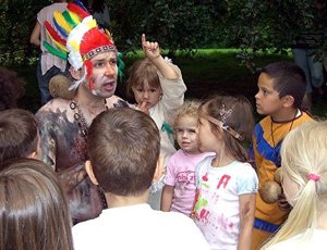 Spielleiter Robert Mingau als Medizinmann Weißer Uhu, umringt von Kindern in Indianerkostümen