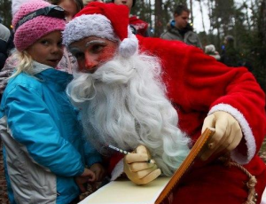 Der Weihnachtsmann beugt sich zu einem Mädchen und schreibt etwas in sein Goldenes Buch