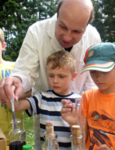 Spielleiter Robert Mingau mit zwei Kindern beim Experimentieren