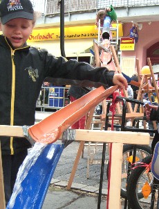 Ein Junge verfolgt aufmerksam das Wasser, das entlang der Röhrenstrecke nach unten rinnt