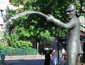 Beispiel-Brunnenfoto: die Brunnenplastik ist oben abgeschnitten, so dass nur die Füße der in den Himmel ragenden Bronzefigur zu sehen sind